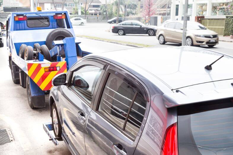 tow-truck-towing-a-broken-down-car-on-the-street-P83U67Q